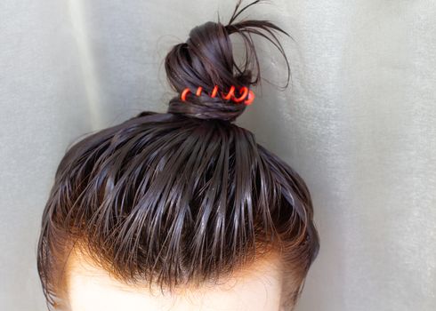 Hair care at home. The girl applied the balm to her hair and gathered her hair into a bun