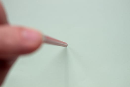 Red pencil. A man holds a red pencil on a light paper with his fingers.