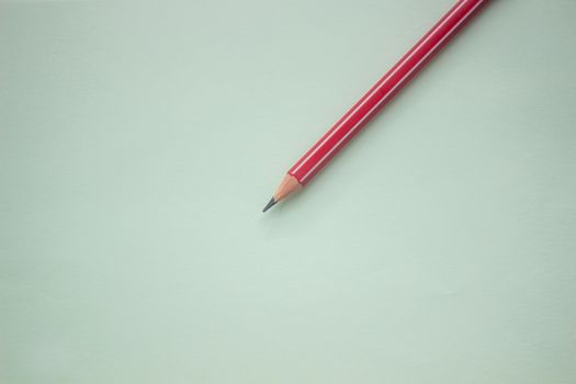 One red pencil on a light green background