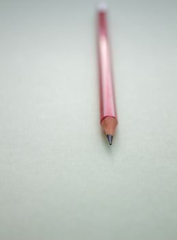 One red pencil on a light green background