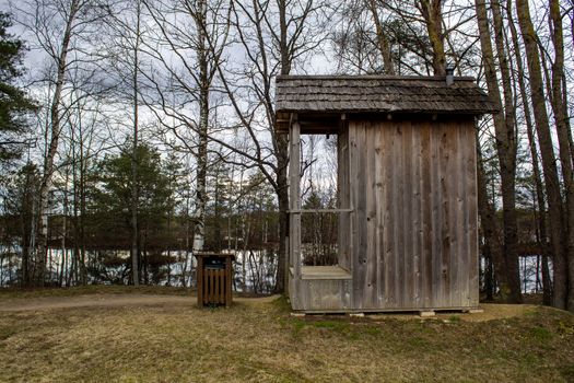 Wooden toilet in nature, near trees and a lake