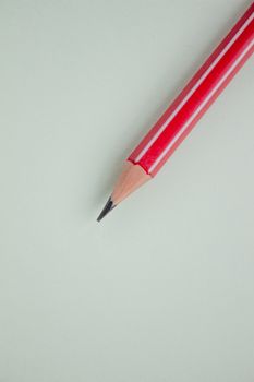 One red pencil on a light green background