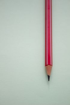 One red pencil on a light green background