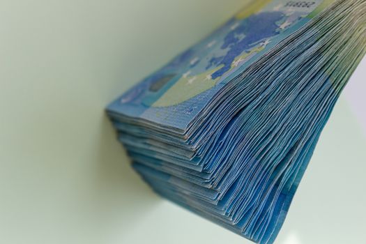 A bundle of 20 Euro banknotes and coins on a light background