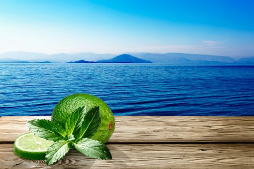 Lime with mint on wooden table against seascape. Ingredients for Mojito. Clipping paths, infinite depth of field
