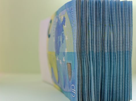 A bundle of 20 Euro banknotes and coins on a light background