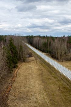 Aerial view from above of country road through the forest.