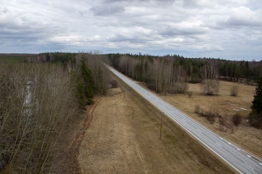 Aerial view from above of country road through the forest.