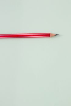 One red pencil on a light green background