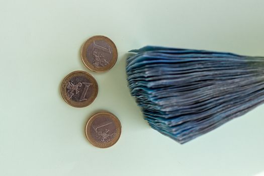 A bundle of 20 Euro banknotes and coins on a light background