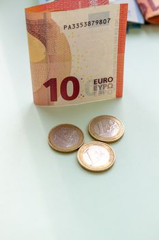 A bundle of 10 Euro banknotes and coins on a light background