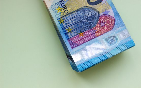 A bundle of 20 Euro banknotes and coins on a light background