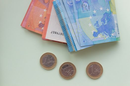 A bundle of 20 Euro banknotes and coins on a light background