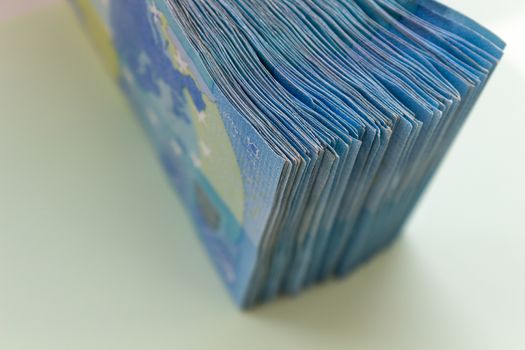 A bundle of 20 Euro banknotes and coins on a light background