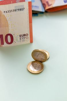 A bundle of 10 Euro banknotes and coins on a light background