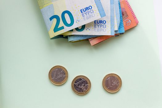 A bundle of 20 Euro banknotes and coins on a light background