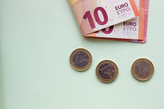 A bundle of 10 Euro banknotes and coins on a light background