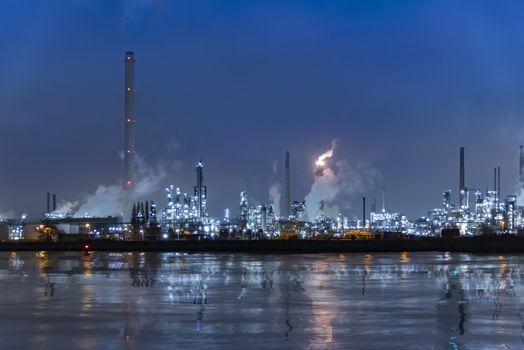 Reflection of refineries and its chimney during the on fire sunset golden hour moment at Rotterdam, Netherlands