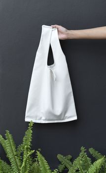 Hand Holding bag canvas fabric for mockup blank template on black wall background.