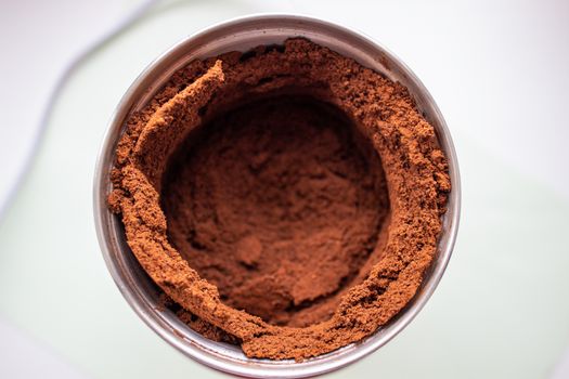 High angle view of fresh coffee pouring out of a coffee grinder into a portafilter for a professional espresso machine