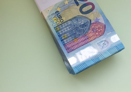 A bundle of 20 Euro banknotes and coins on a light background