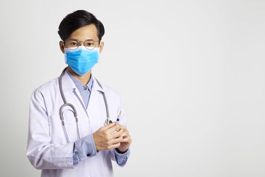 attractive asia man doctor wearing surgical mask and hand holding vaccine syringe standing in gray wall background. Concept Preventive measures against corona virus.