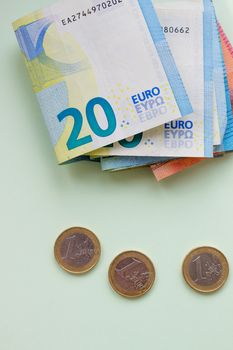 A bundle of 20 Euro banknotes and coins on a light background