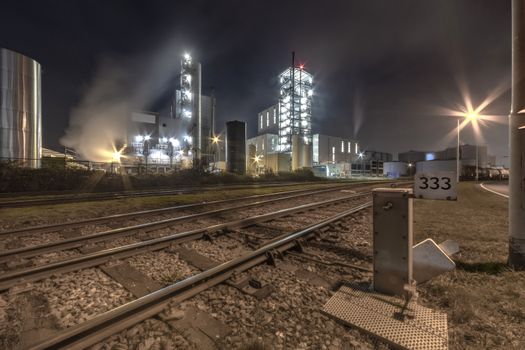 Night view of an industrial zone with the rail road checkpoint transporting in and out raw material