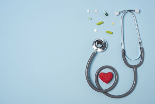 medical equipment stethoscope with red heart and drug on blue copy space background.