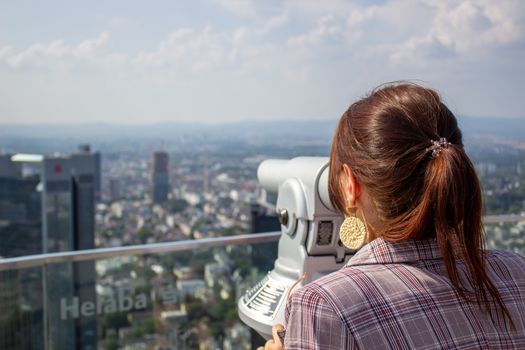 Young tourist girl with looking at the Frankfurt from the top of the main tower. Aerial View Frankfurt am Main from main tower to financial center