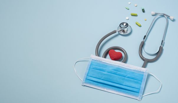 medical equipment stethoscope with red heart and drug, surgical mask on blue copy space background.