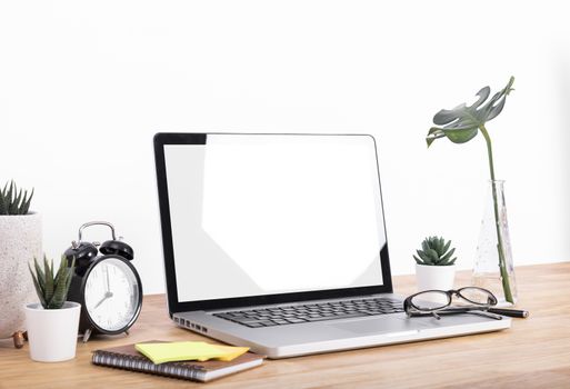 Mockup Blank screen notebook computer and decorations on wood table and white wall background.