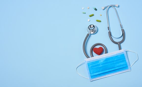 medical equipment stethoscope with red heart and drug, surgical mask on blue copy space background.