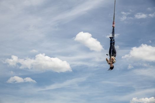 SCHEVENINGEN, 2 June 2019 - Bungee jumper jump from a platform hanging on the crane into the water against a pur blue spring sky of The Hague, Netherlands
