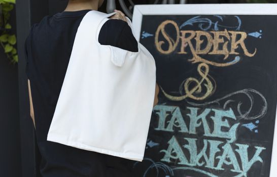 Man is holding bag canvas fabric for mockup blank template on restaurant background.