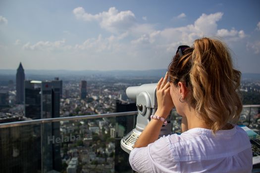 Young tourist girl with looking at the Frankfurt from the top of the main tower. Aerial View Frankfurt am Main from main tower to financial center