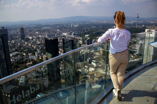 Young tourist girl with looking at the Frankfurt from the top of the main tower. Aerial View Frankfurt am Main from main tower to financial center