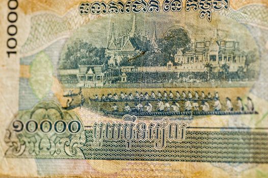 A Cambodian banknote for 10,000 Riels showing a water festival in front of the Royal Palace. Used note, photographed at an angle