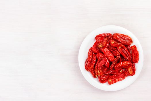 Sun dried tomatoes on bleached wooden table. Top view, flat lay