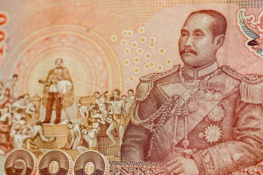 Detail of a 100 Baht banknote from Thailand showing His Majesty King Chulalongkorn (Rama V) in navy uniform and also in a scene marking the abolition of slavery.