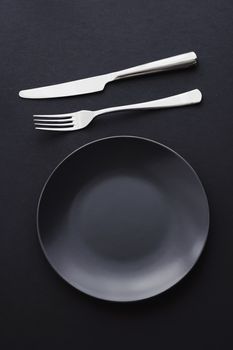 Empty plates and silverware on black background, premium tableware for holiday dinner, minimalistic design and diet concept