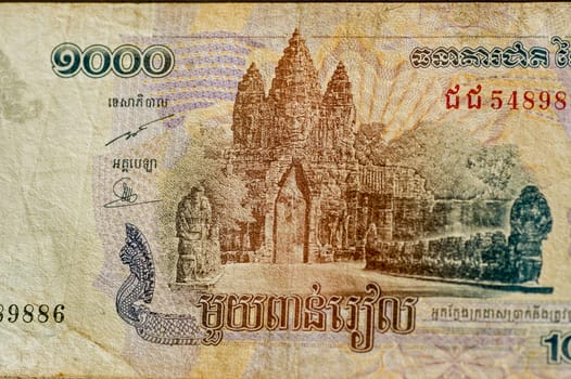 Part of a One Thousand Riels banknote from Cambodia showing the Victory Gate at Angkor Thom, part of the UNESCO World Heritage Site of Angkor. Used banknote, photographed at an angle.