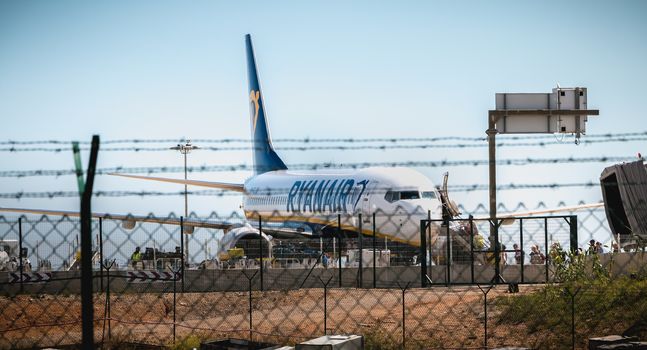 Faro, Portugal - May 3, 2018: behind the outer gates, planes parked on the tarmac of Faro International Airport on a spring day