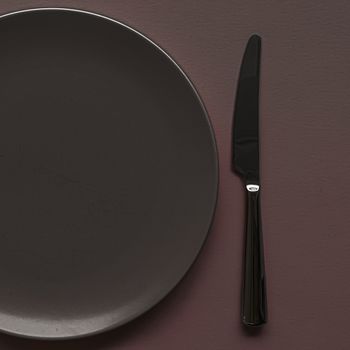 Empty plate and cutlery as mockup set on dark brown background, top tableware for chef table decor and menu branding design