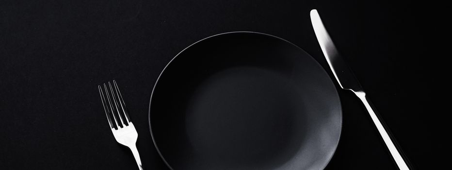 Empty plates and silverware on black background, premium tableware for holiday dinner, minimalistic design and diet concept