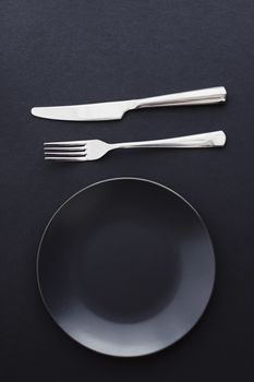 Empty plates and silverware on black background, premium tableware for holiday dinner, minimalistic design and diet concept