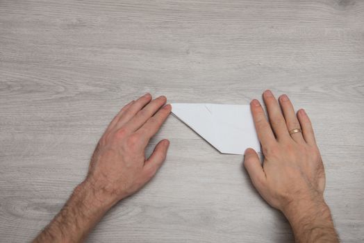 steps of making origami paper airplane on wooden table with arms