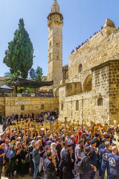 Jerusalem, Israel - April 6, 2018: Orthodox good Friday scene in the entry yard of the church of the holy sepulcher, with pilgrims carrying crosses. The old city of Jerusalem, Israel