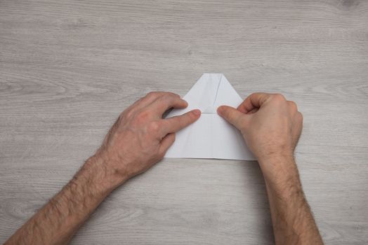 steps of making origami paper airplane on wooden table with arms