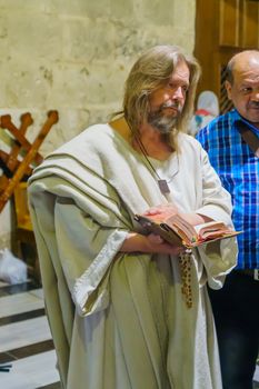 Jerusalem, Israel - April 6, 2018: Orthodox good Friday scene in the church of the holy sepulcher, with a pilgrim dress like Jesus. The old city of Jerusalem, Israel